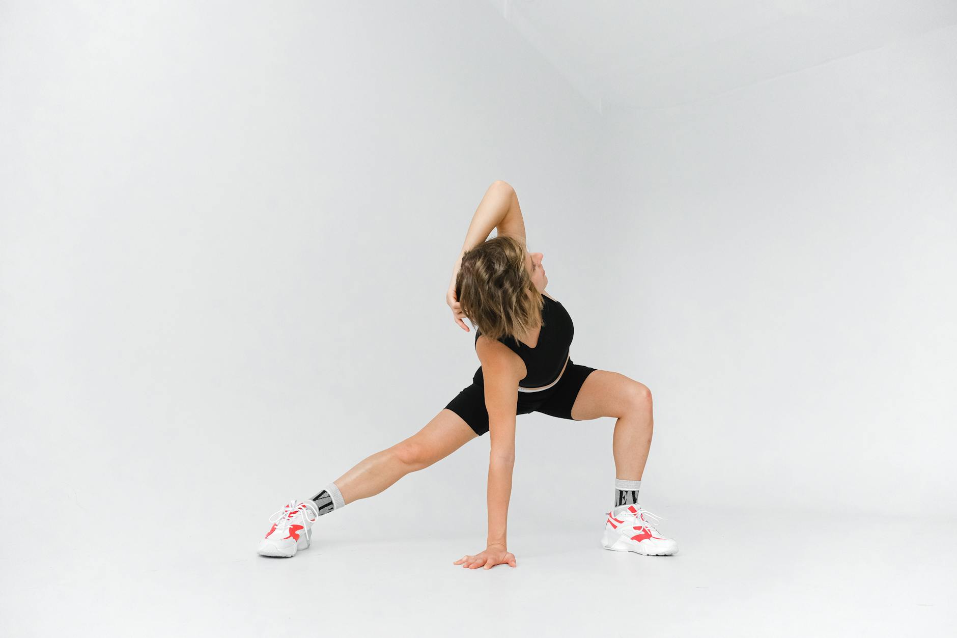 Female athlete performs flexibility exercises in a sleek, white studio environment.
