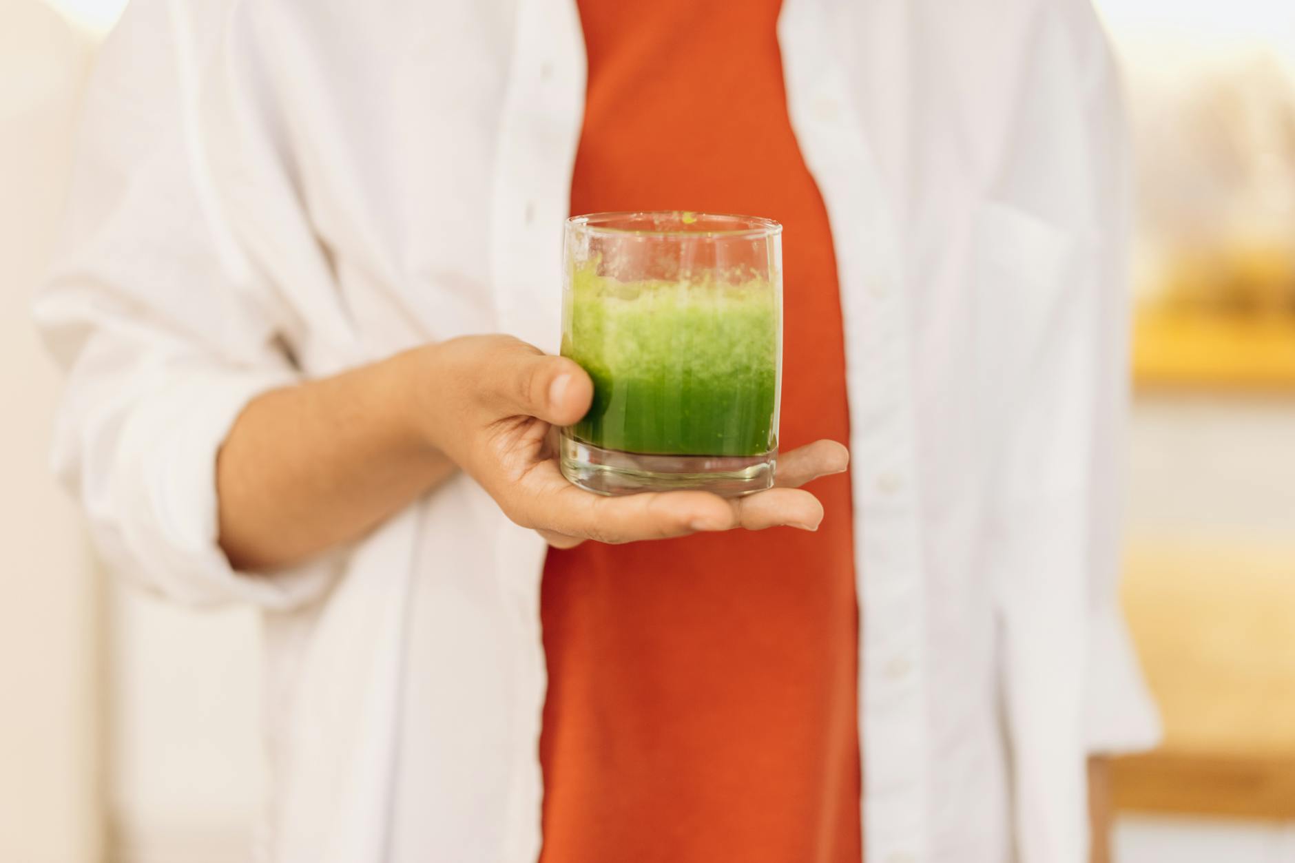 Close-up of a person holding a refreshing green smoothie, symbolizing a healthy lifestyle.
