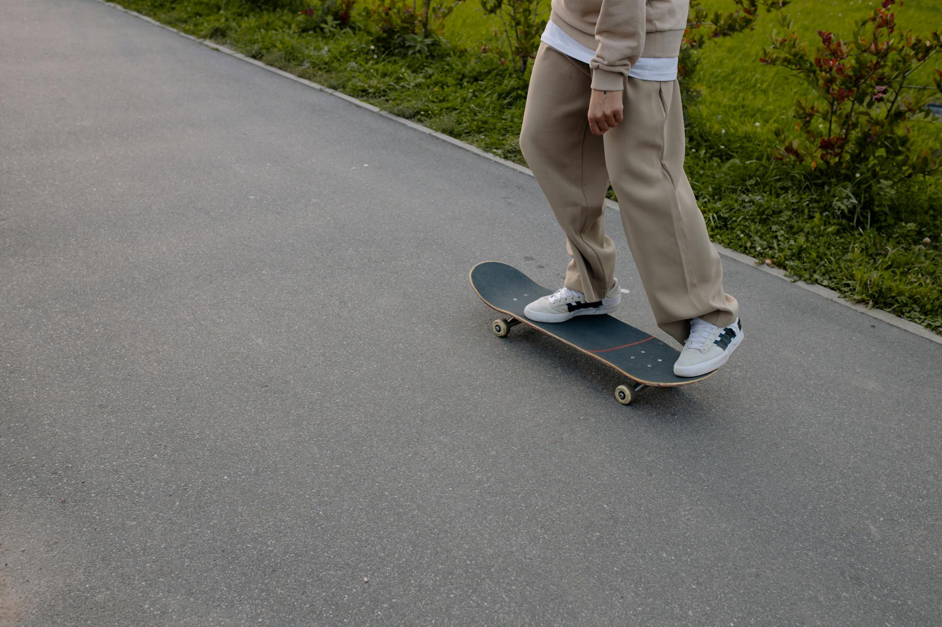A person casually skateboarding on a path in an outdoor urban park setting during the day.