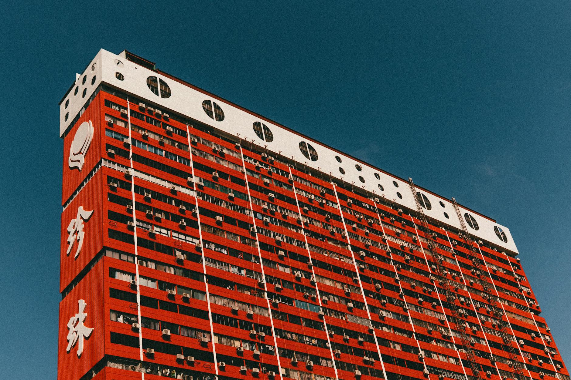 A striking red residential building with architectural details against a clear blue sky.