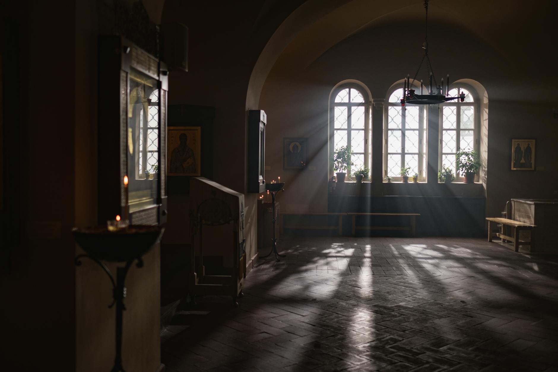 Sunlight streams through church windows highlighting religious icons in a serene atmosphere.