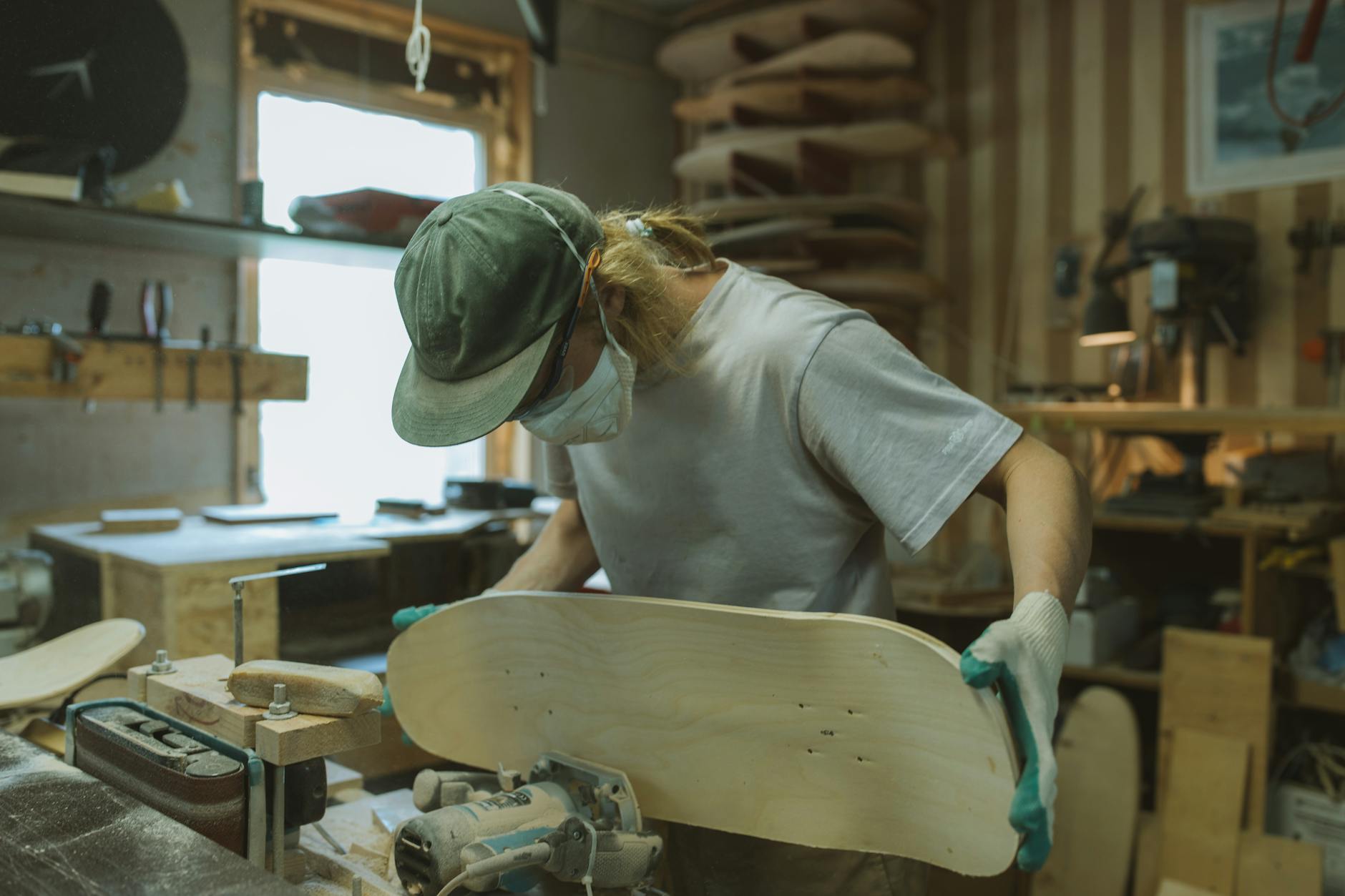 A skilled craftsman uses a router to shape a skateboard deck in a workshop.