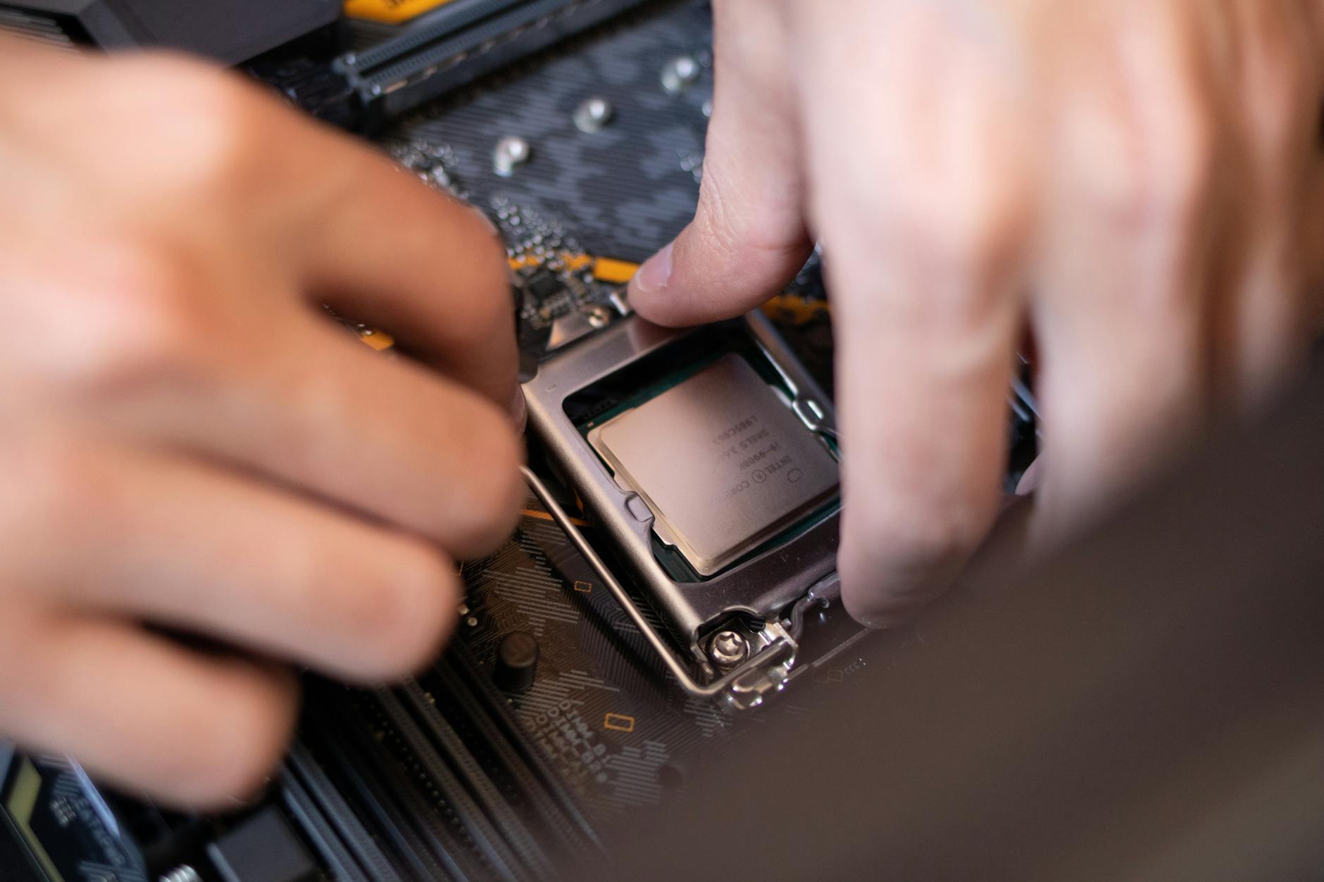 Detailed view of hands installing a CPU onto a motherboard inside a computer setup.