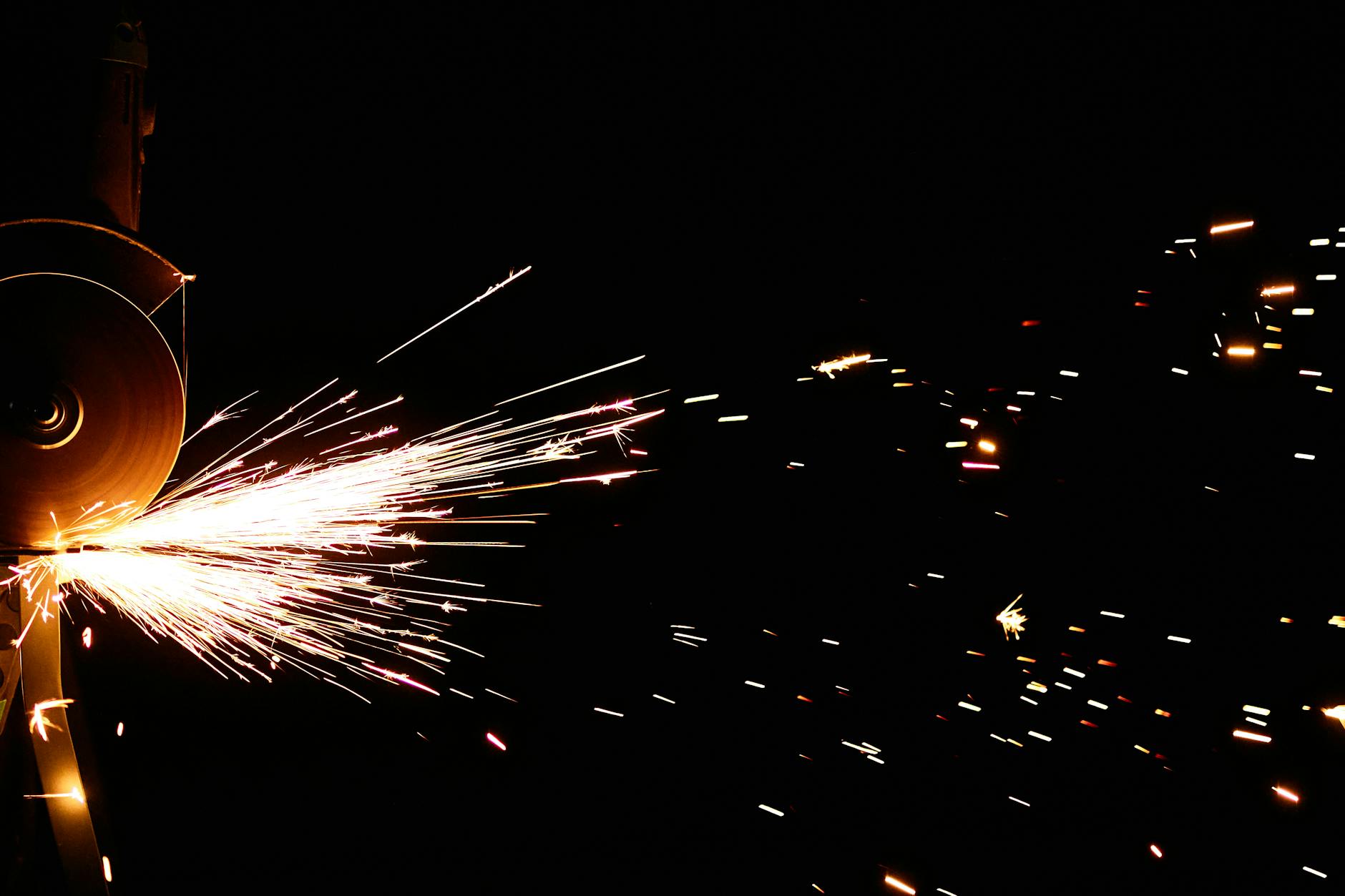 Vibrant sparks fly from an angle grinder cutting in a dark setting.